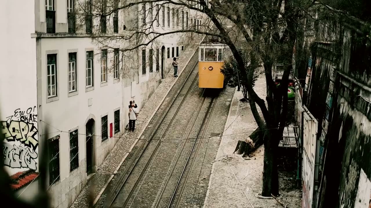 A yellow tram climbing a Lisbon street